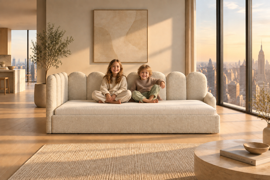 Beige sofa with cushions and a blanket against a beige paneled wall.
